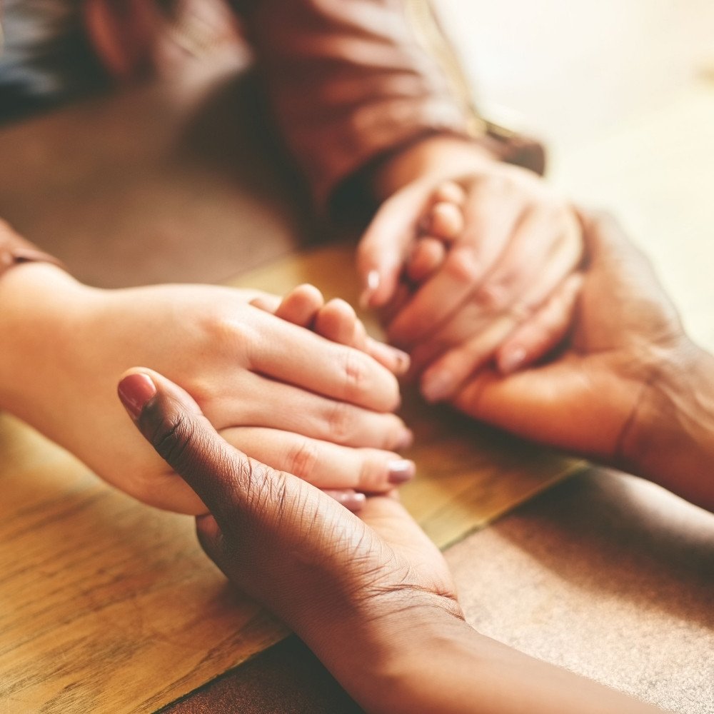Two people holding hands in a comforting gesture representing healing and emotional support