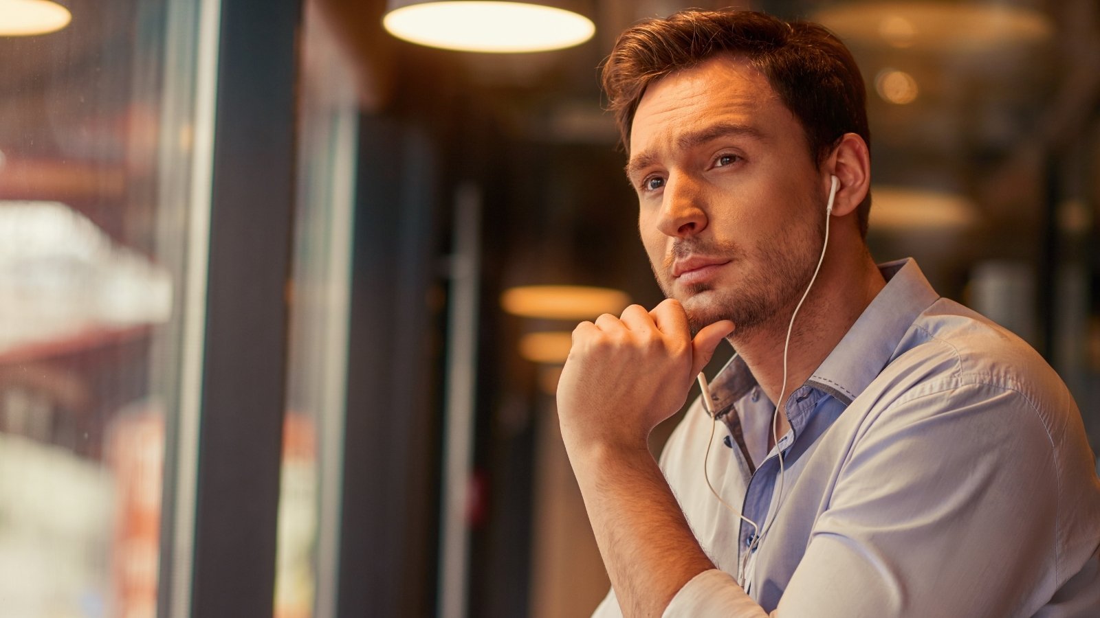 Thoughtful man in contemplative moment by window reflecting on personal relationships and friendships