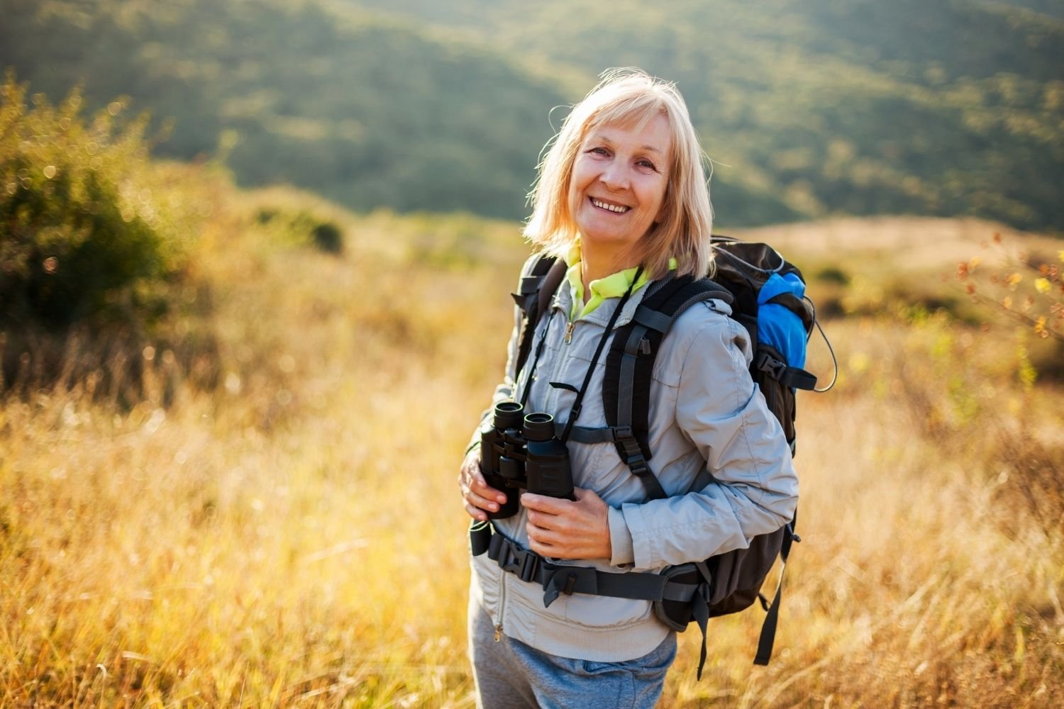 Woman hiker with binoculars visualizing her goals and manifesting outdoor adventures